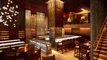 A modern interior with a bar area, seating, and a staircase.