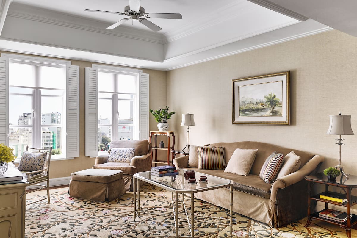 Un salon bien éclairé, avec un canapé, des fauteuils, une table basse et un lampadaire.