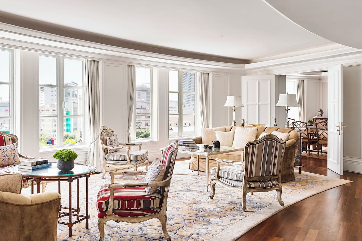 Un salon spacieux doté de grandes fenêtres, d’un mobilier élégant et offrant une vue sur la ville.