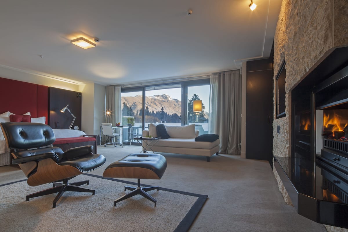 Una sala de estar moderna con chimenea, asientos de cuero, un sofá y un ventanal con vistas a la montaña.