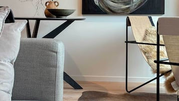 A modern living room with a grey sofa, a black coffee table, a painting, and a fur rug.