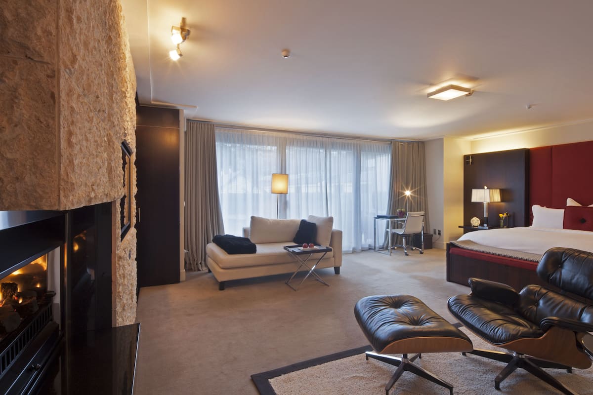Una habitación de hotel con chimenea, un sofá, un sillón de cuero, una cama y un escritorio.