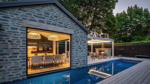 A modern house with a swimming pool, stone exterior, and a dining area with outdoor seating. - The Spire Hotel Queenstown (Queenstown)