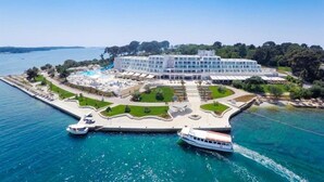 Un hotel moderno y espacioso con un patio central, varias piscinas y un muelle para embarcaciones.