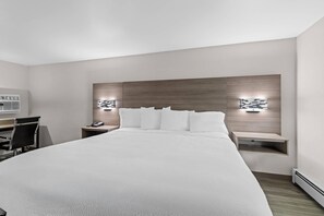 A modern hotel room with a large bed, a desk, and a chair. There are two bedside tables with lamps. - Econo Lodge (Westminster)