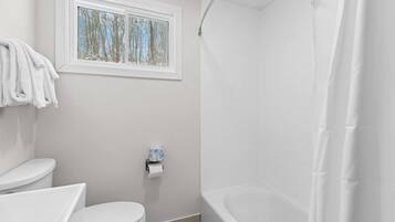 Un baño con inodoro, ventana y bañera.