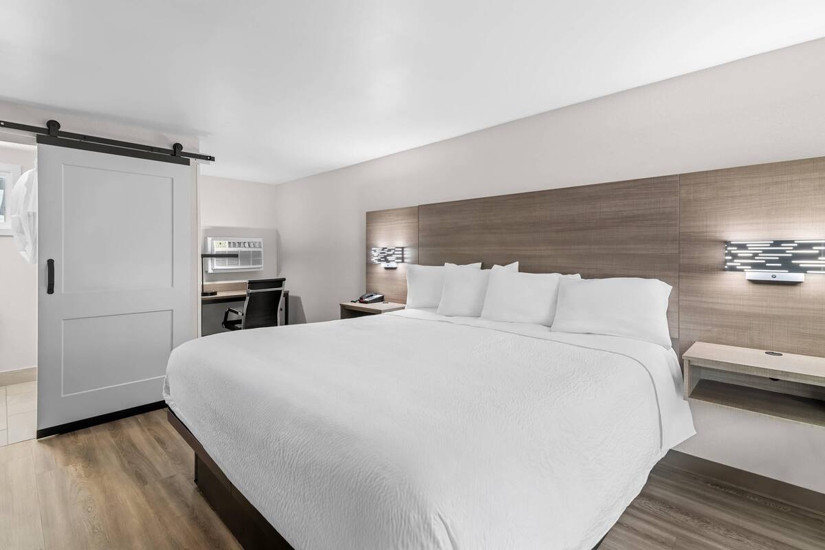 Une chambre d’hôtel moderne, dotée d’un grand lit, d’un bureau et d’un téléviseur fixé au mur.
