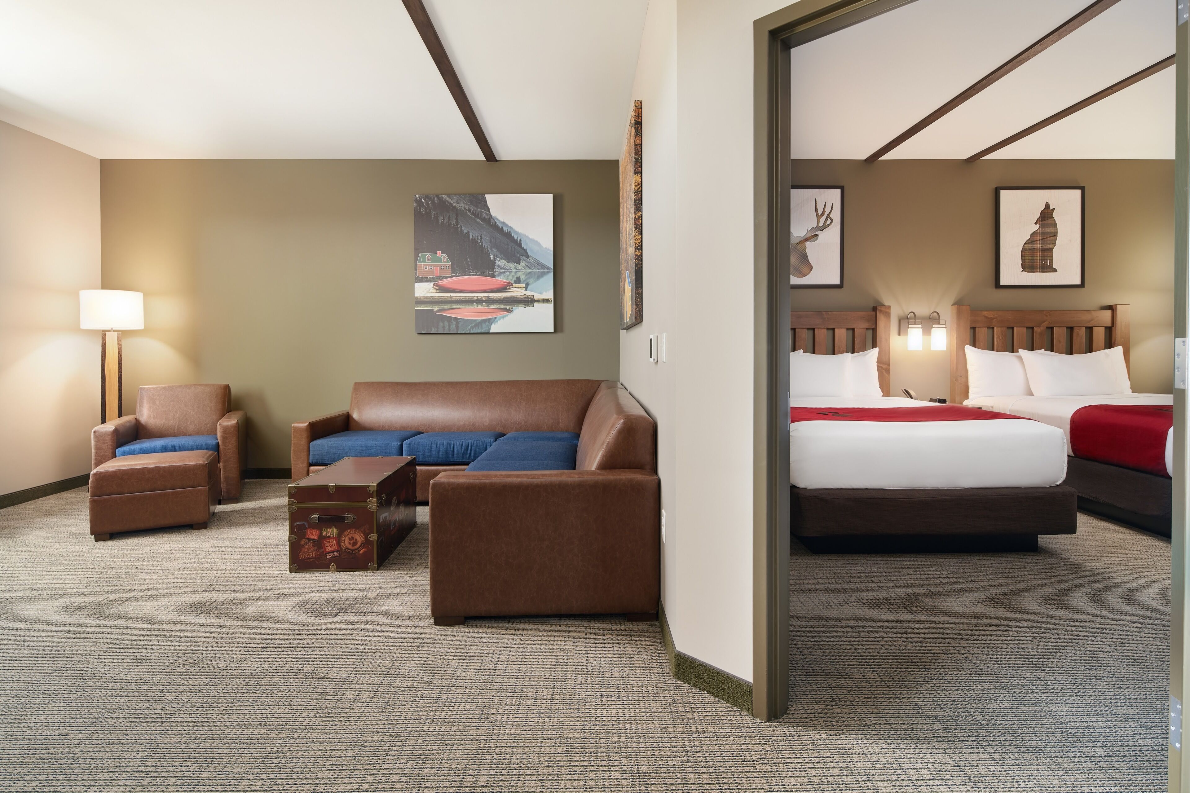 Een hotelkamer met een bed, een bank, een stoel, een klein tafeltje en kunst aan de muren.