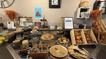 Un bufé con diversos alimentos, incluyendo bollería, pan y salsas.