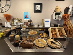 A buffet with various food items, including pastries, bread, and condiments. - Brit Hotel Besançon L'Horloge (Besancon)