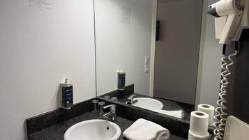 A bathroom with a white sink, a mirror, a hairdryer, and a towel.
