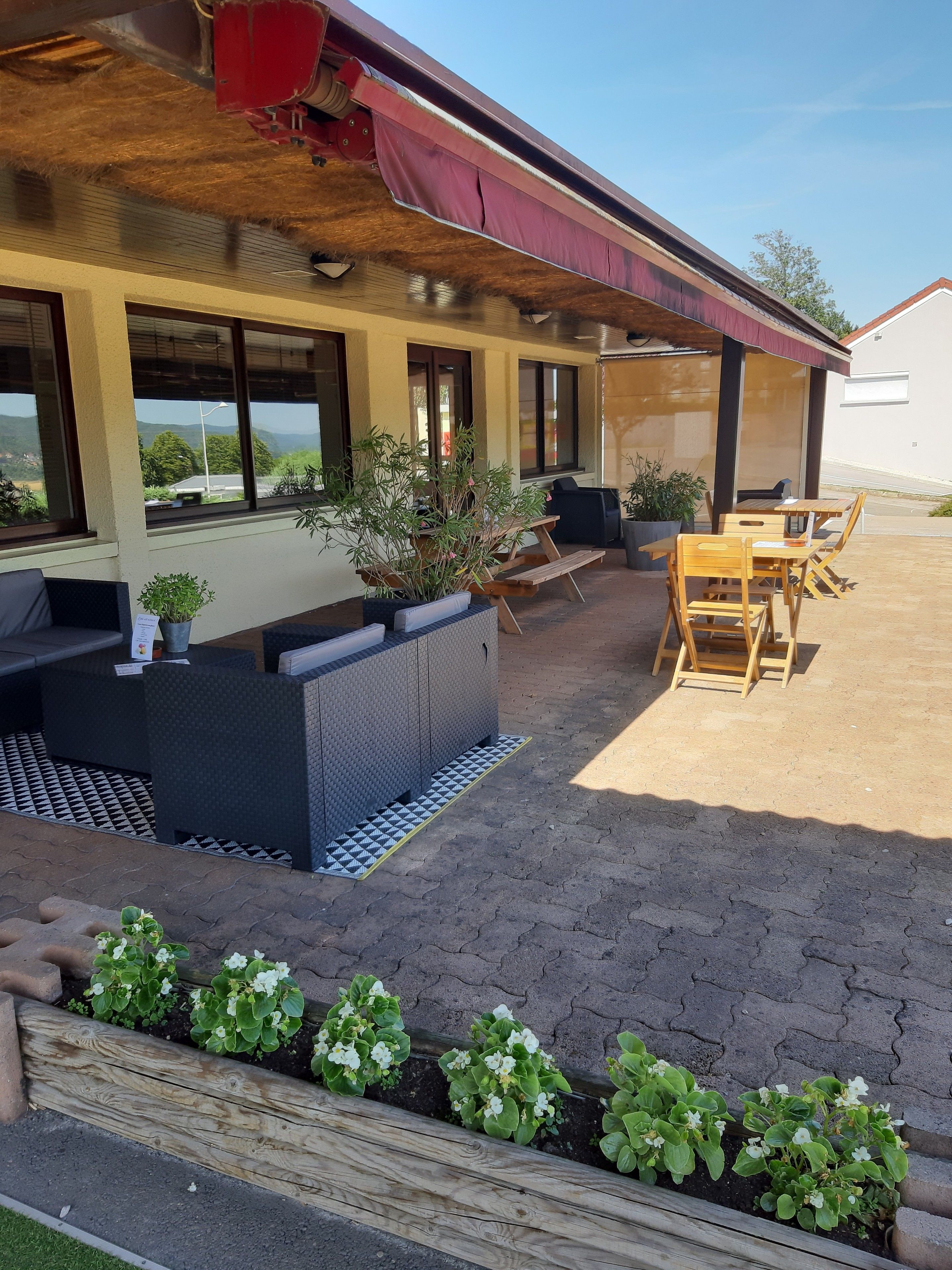 Un patio al aire libre con una mesa y sillas de madera, un banco incorporado y plantas en macetas.
