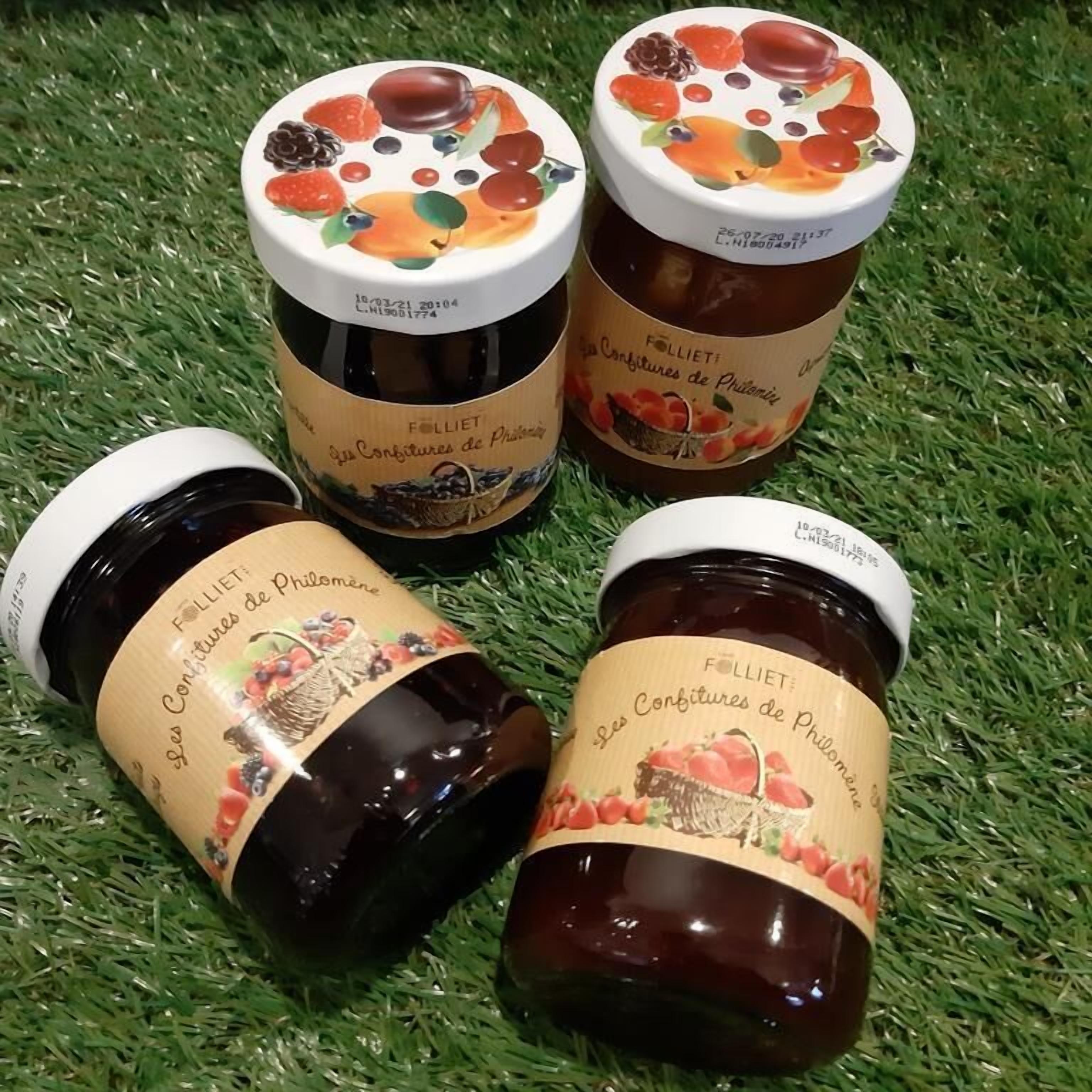 Cuatro frascos de mermelada con etiquetas sobre una superficie cubierta de hierba.