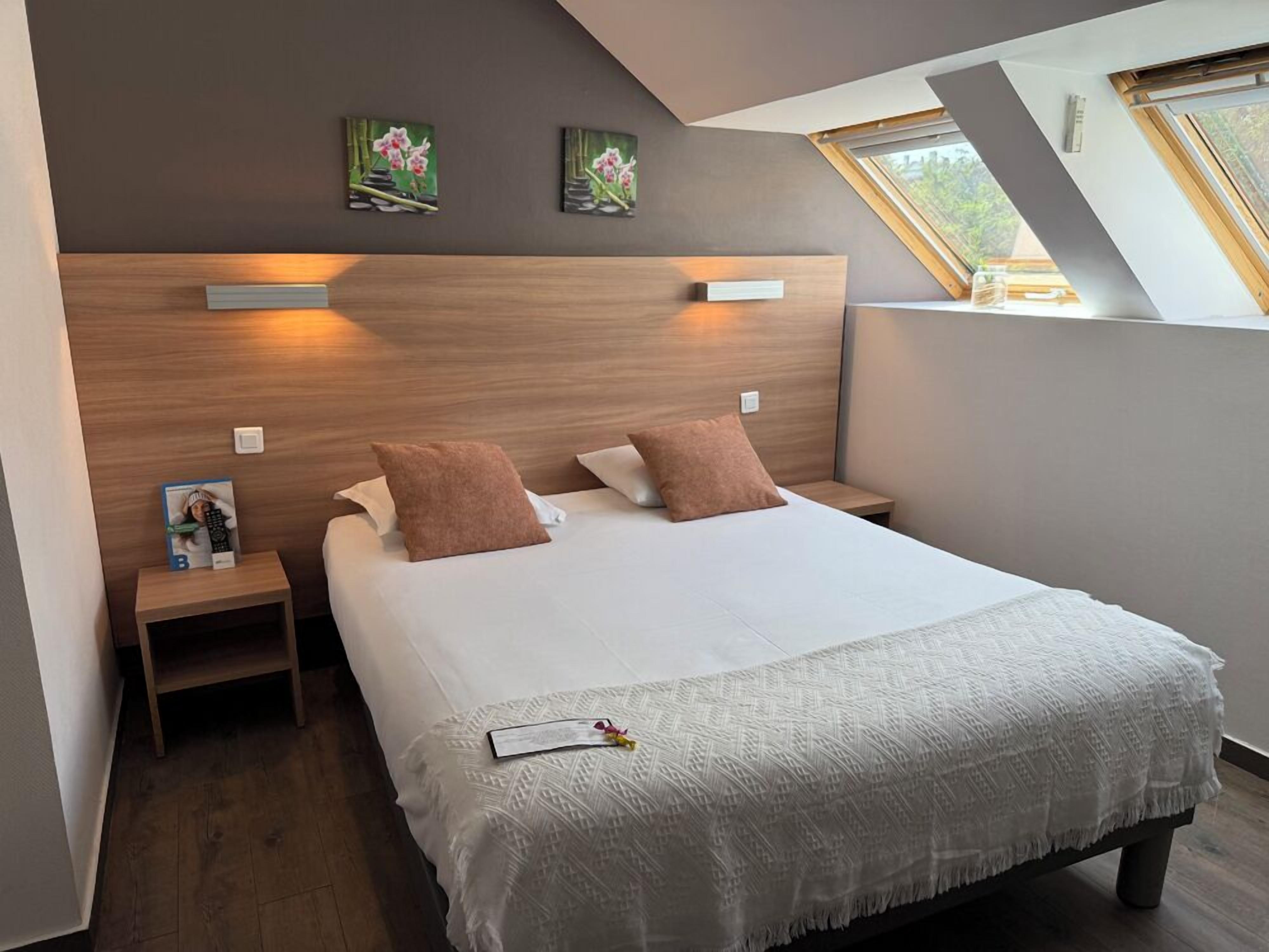 Quarto moderno com uma cama grande, duas mesas de cabeceira, um painel de cama de madeira e um claraboia.