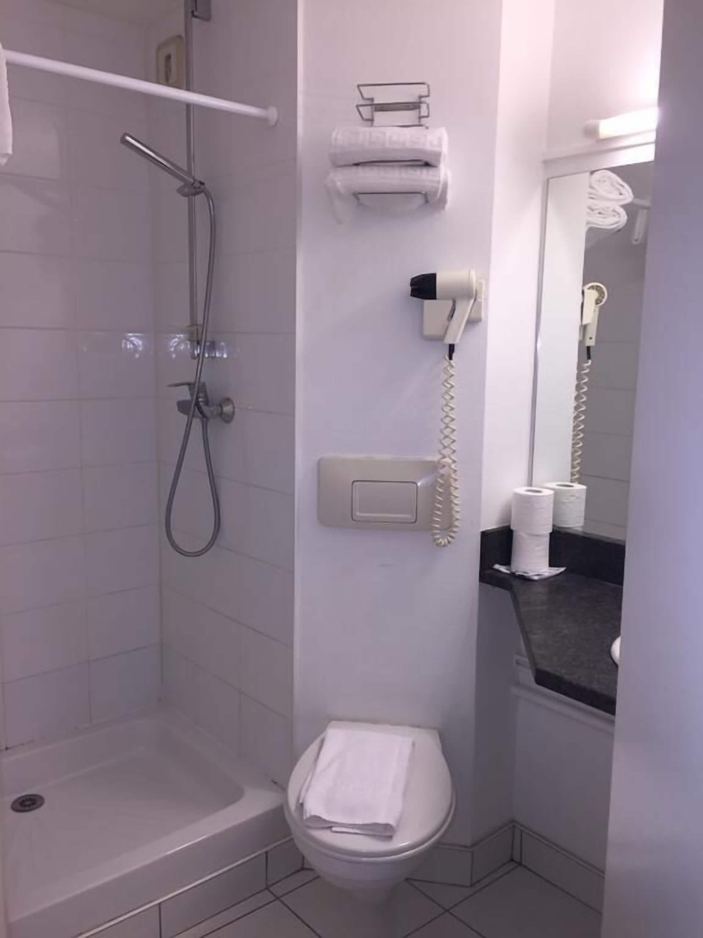 Un baño con ducha, inodoro y toallero.
