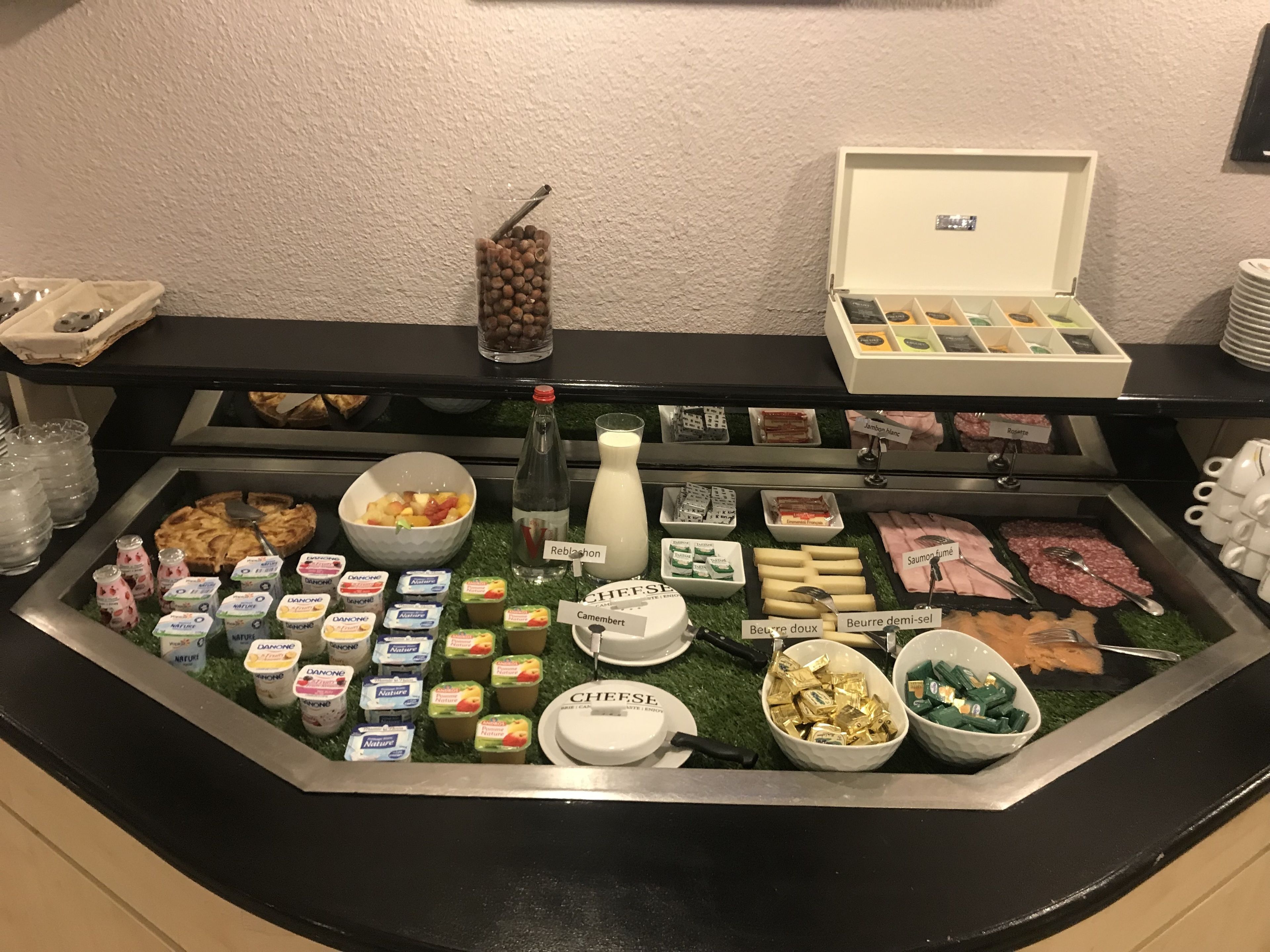 A buffet with various food items including fruits, cheeses, meats, and dairy products.