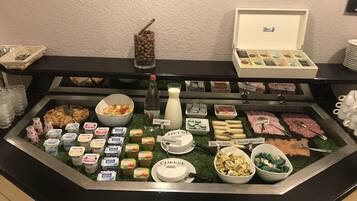 A buffet with various food items including fruits, cheeses, meats, and dairy products.