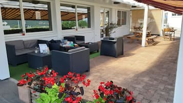 An outdoor patio with seating, a table, and planters with red flowers.