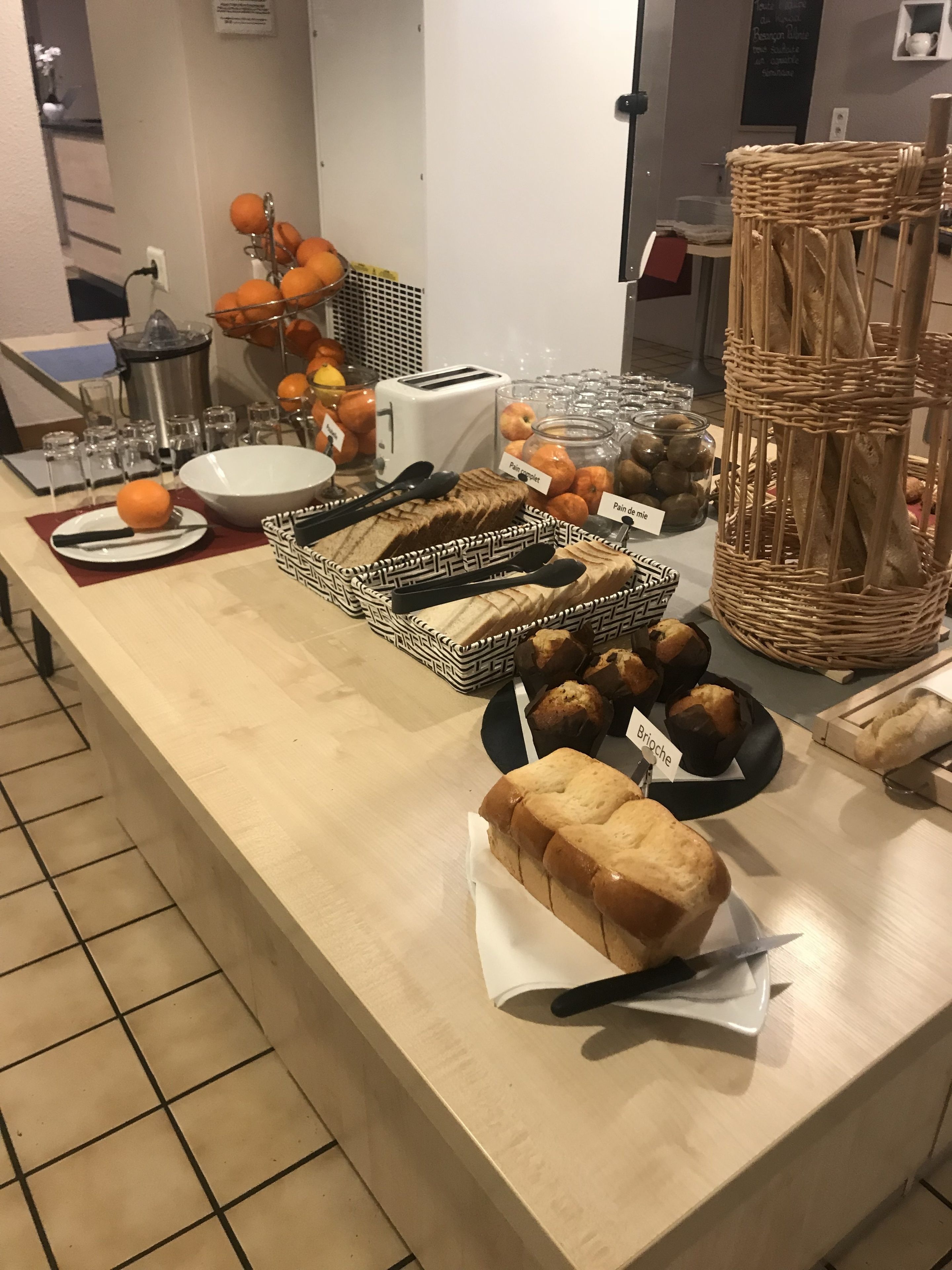 Noutopöytä, jossa on tarjolla monenlaista ruokaa, kuten leipää, leivonnaisia ja appelsiineja.
