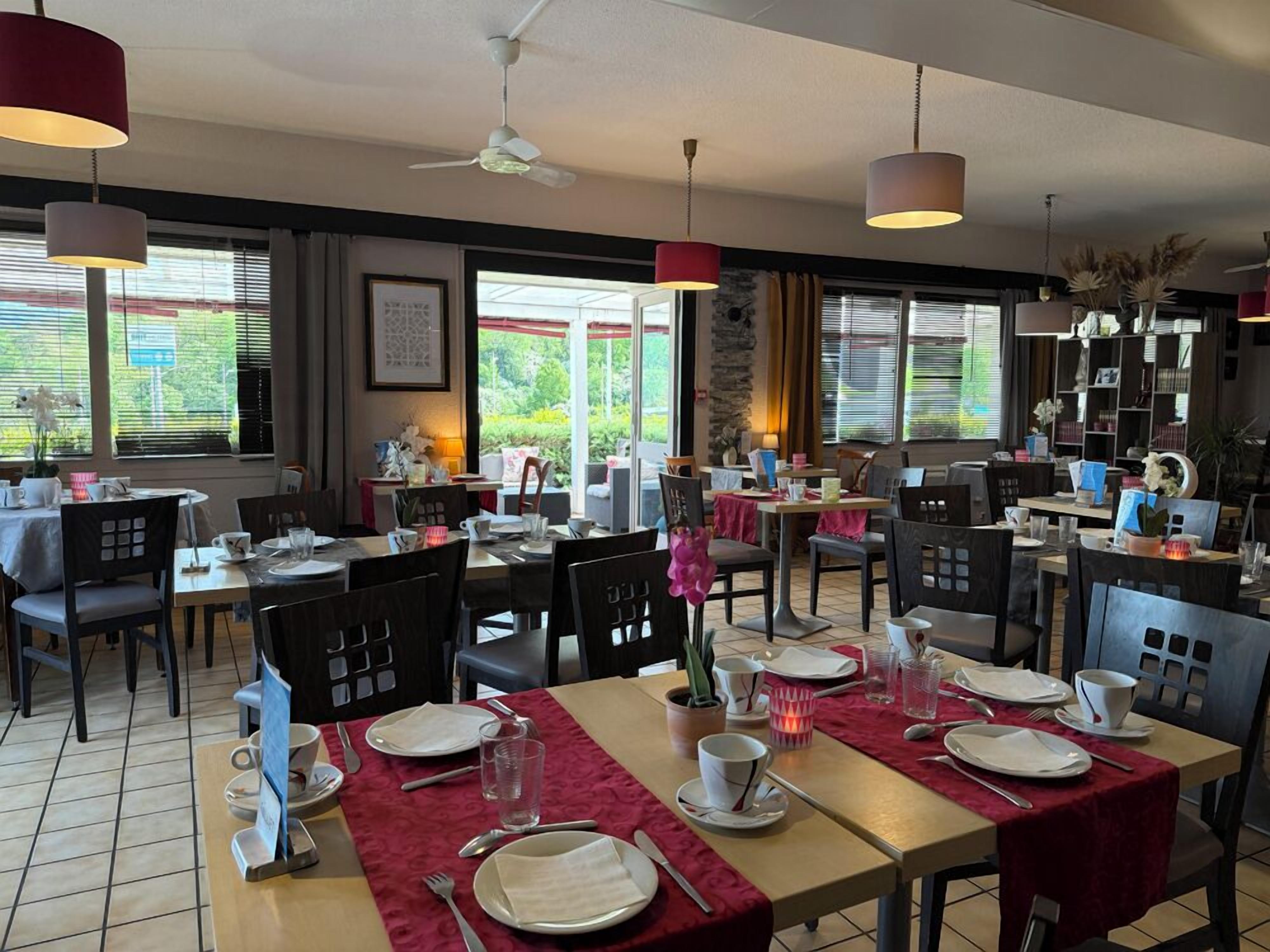 Een restaurant met meerdere tafels, stoelen en hangende lampen.