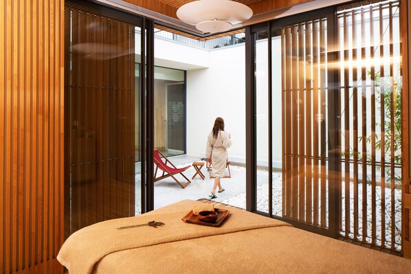 Habitación con puerta de vidrio corredera que da a un espacio exterior con una silla roja y una mesa.
