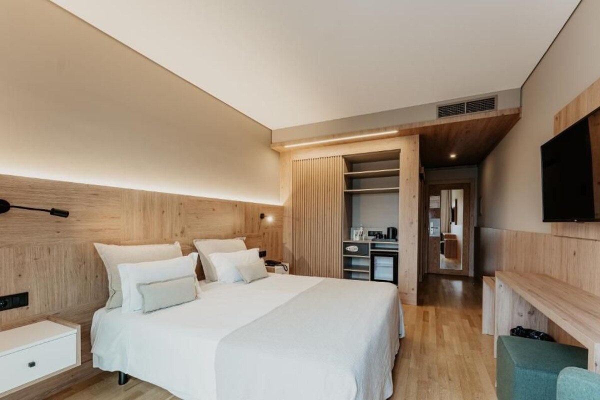Un dormitorio moderno con una cama grande, cabecera de madera y un vestidor.