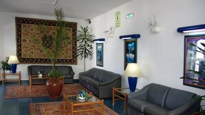 Una sala de estar con un sofá, una mesa de centro, una alfombra y una planta grande.