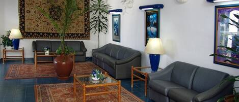 Una sala de estar con un sofá, una mesa de centro, una alfombra y una planta grande.