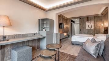 Una habitación de hotel moderna con techo de madera, un sofá, una mesita y una cama.