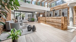 A spacious, modern interior with a high ceiling, wooden accents, and large windows allowing natural light. - Natur & Spa Hotel Lärchenhof (Seefeld in Tirol)