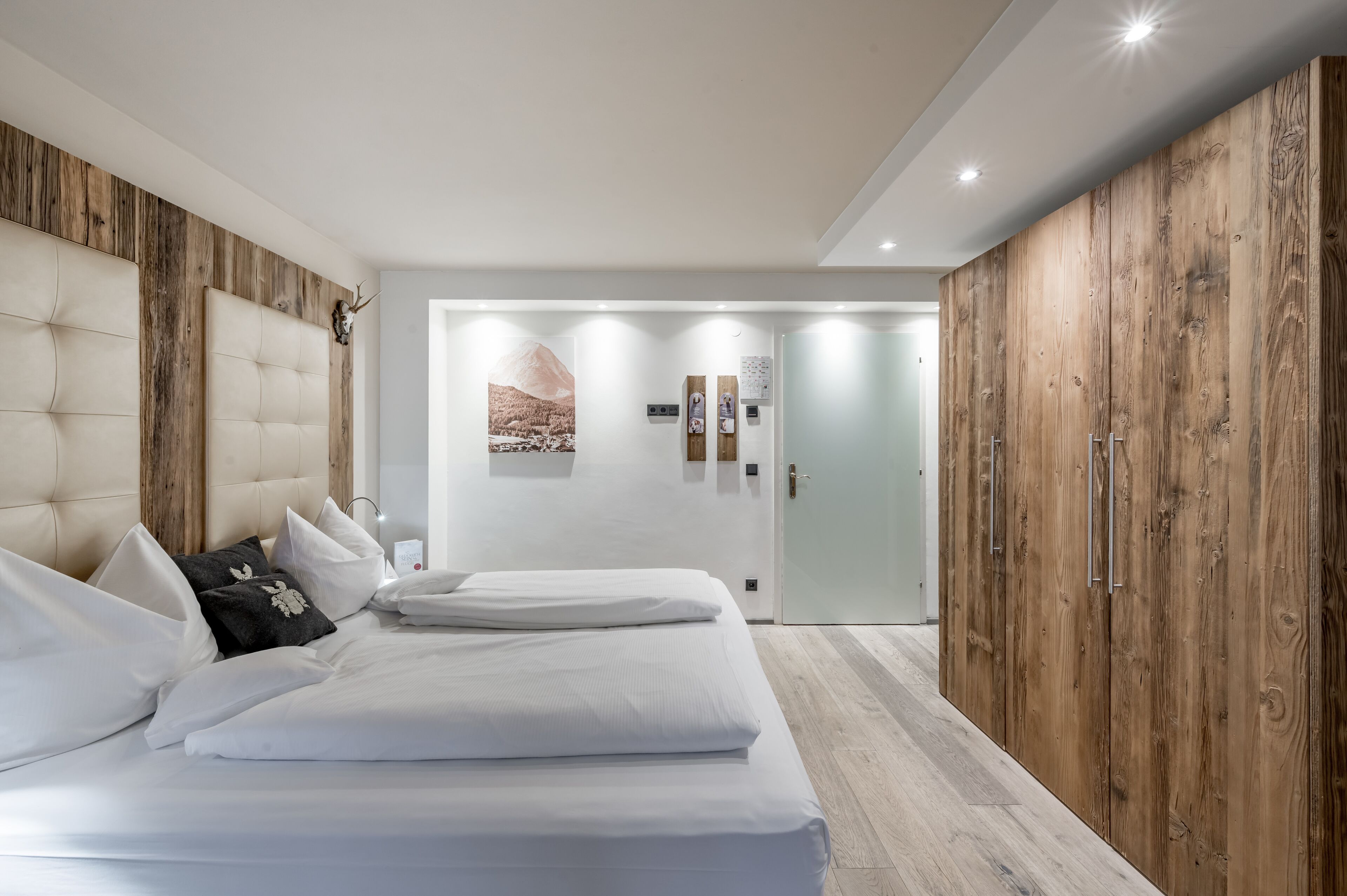 A modern bedroom with a large bed, wooden panel walls, and a minimalist design.