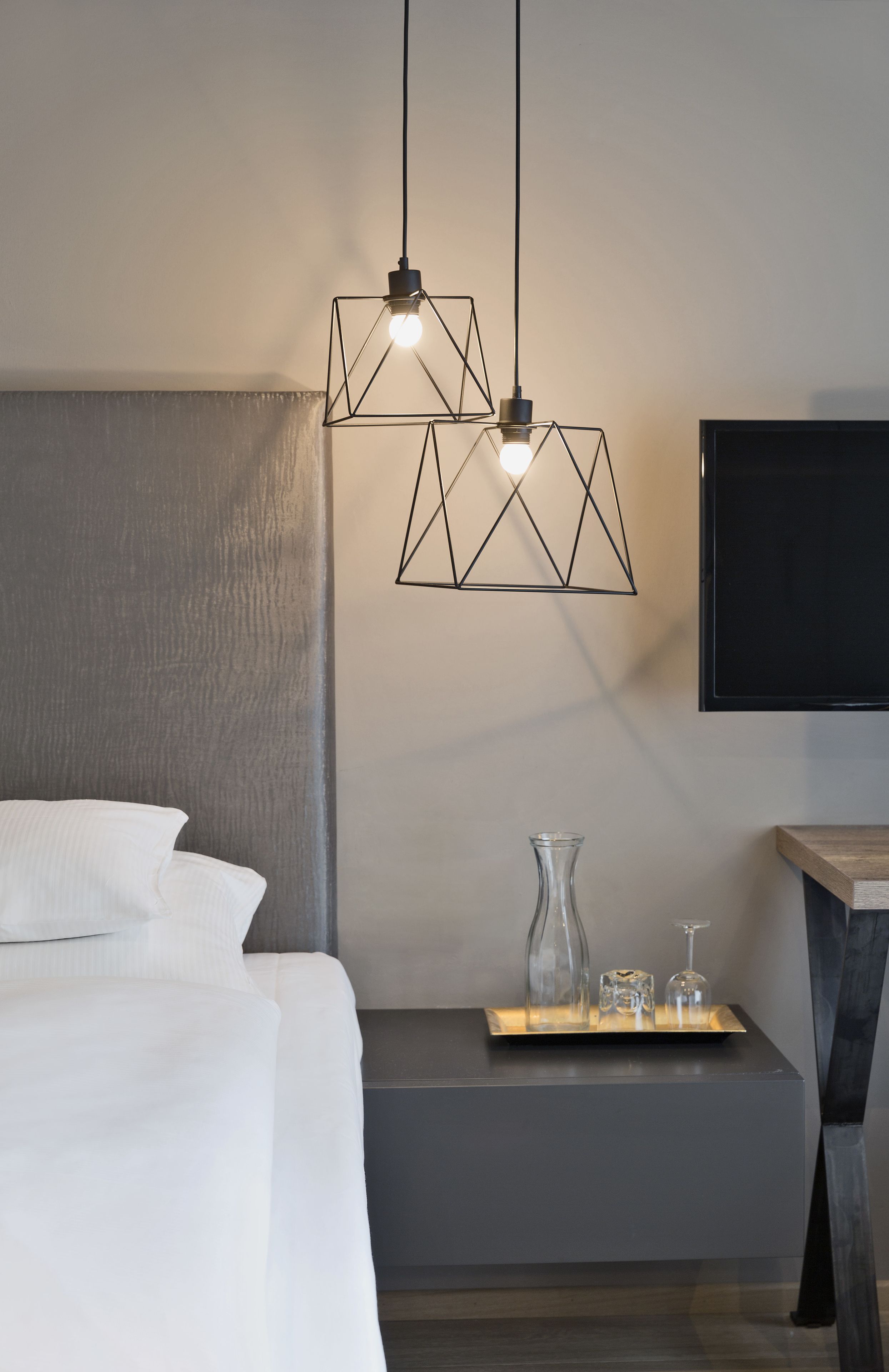 Une chambre à coucher moderne avec un lit, une table de chevet et un téléviseur fixé au mur.