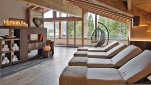 A modern interior with wooden beams, a fireplace, and a seating area with cushions. - Natur & Spa Hotel Lärchenhof (Seefeld in Tirol)