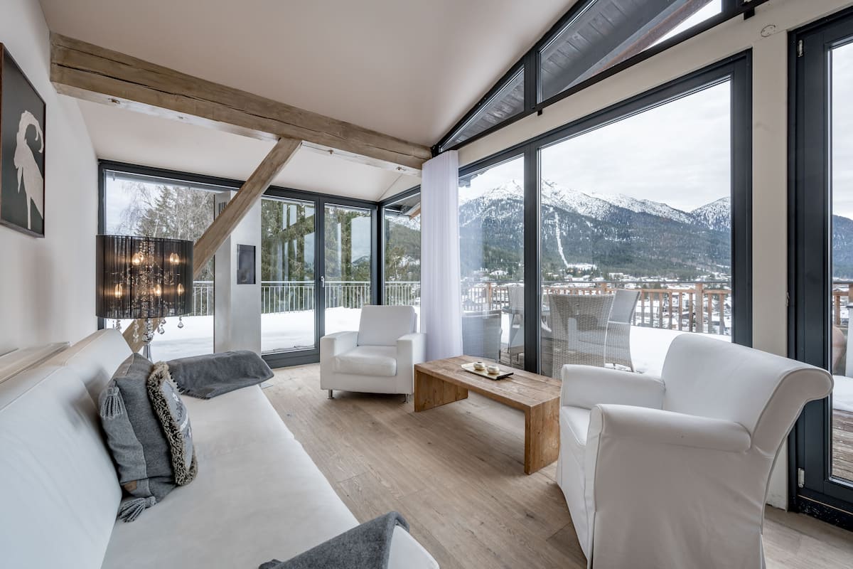 A modern living room with a large window, white furniture, and a wooden coffee table.