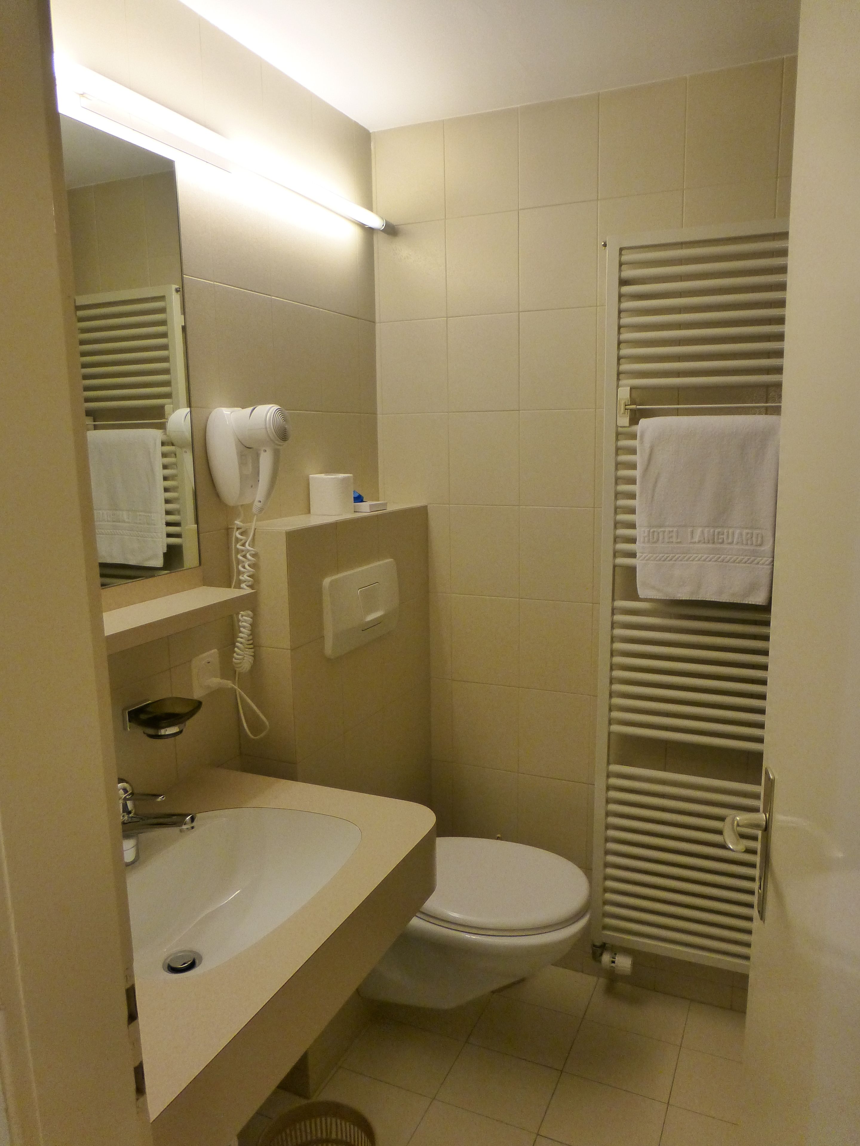 A compact bathroom with a sink, toilet, and a towel rack with a towel.
