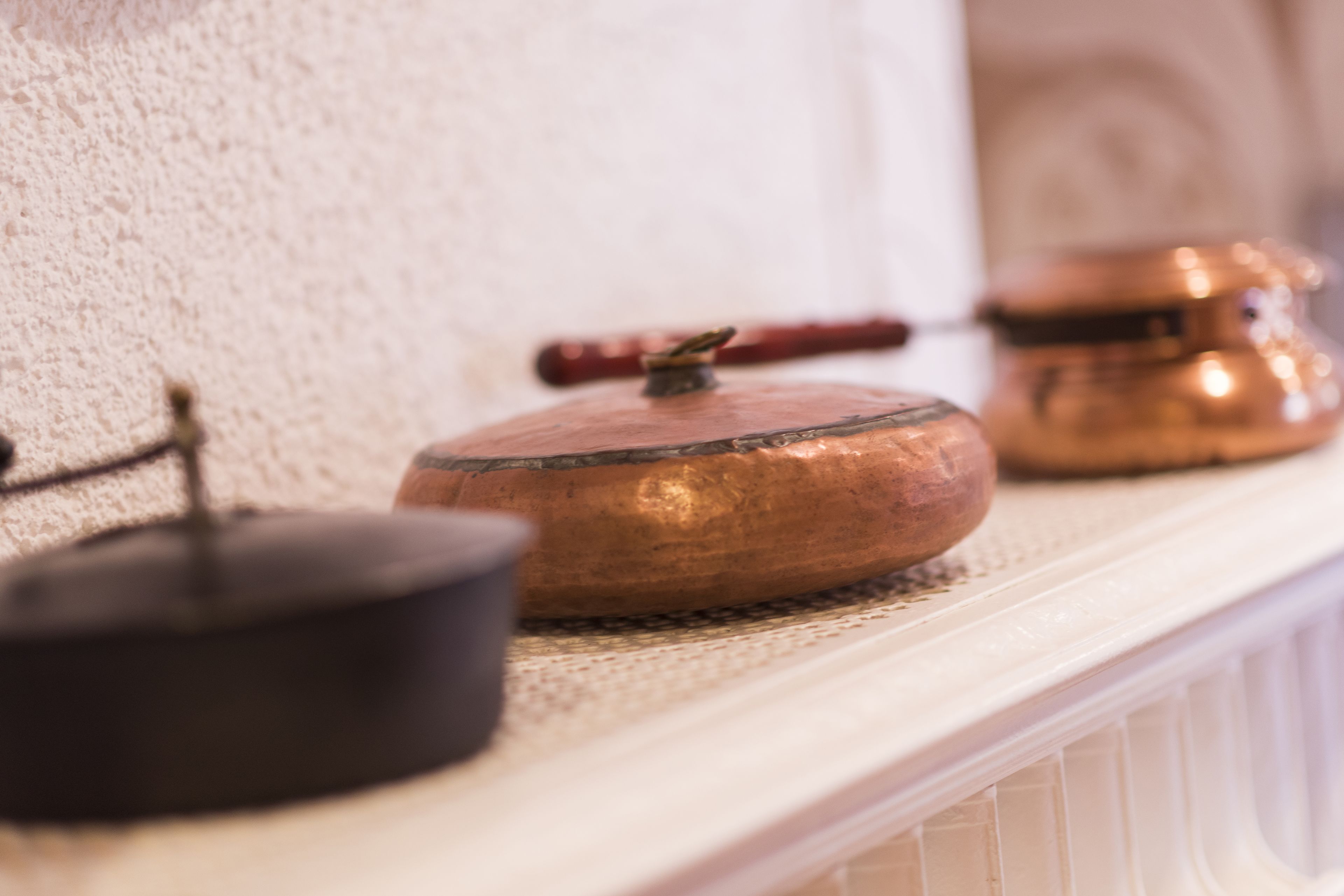 A kitchen with a white countertop, a copper pot, and a black pot.