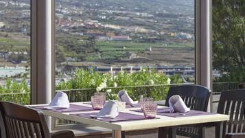 A table set for two with a view of a mountainous landscape.