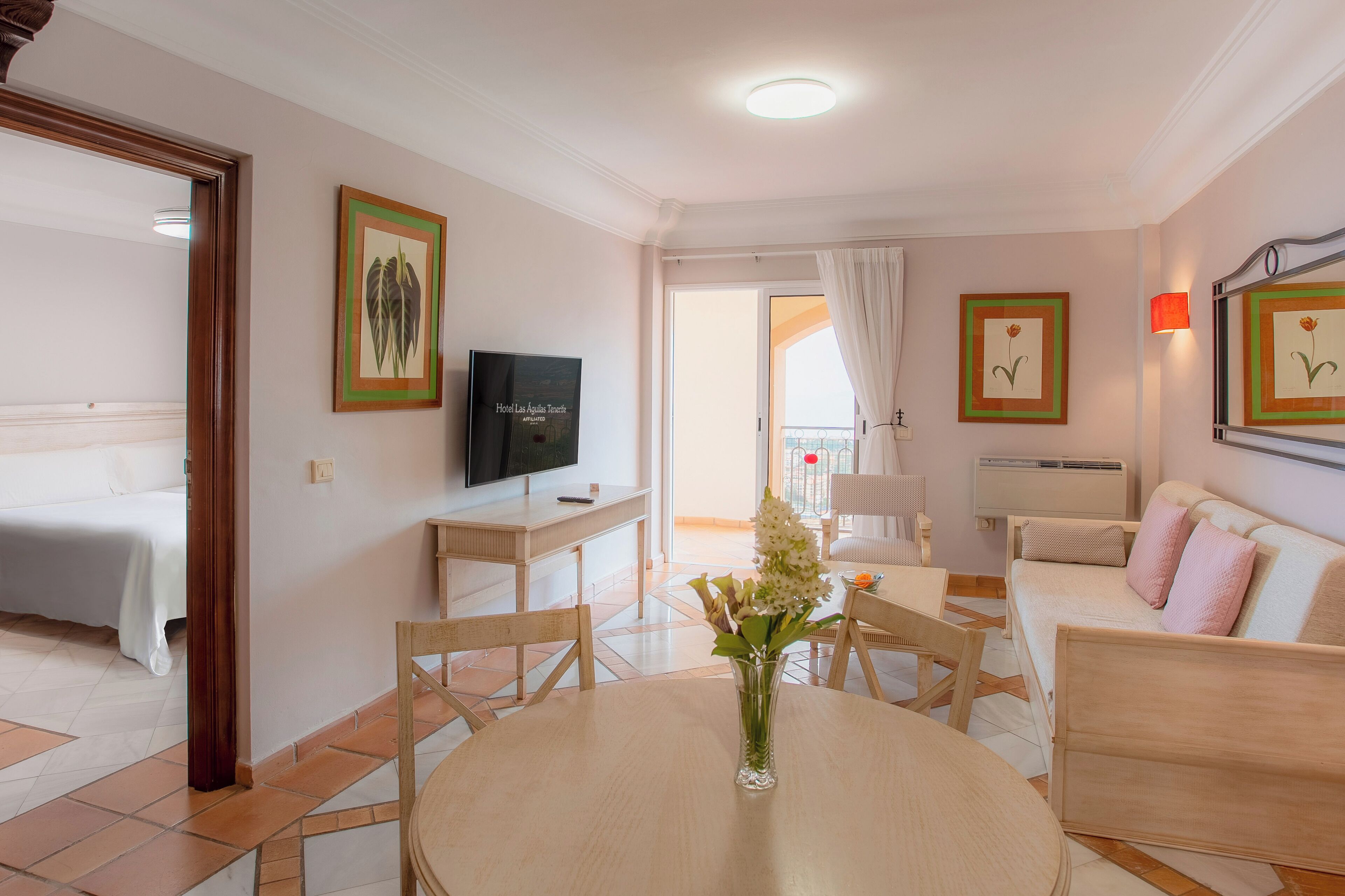 Une chambre d’hôtel comprenant un lit, une télévision, une table à manger avec des chaises, un canapé et un balcon avec vue.