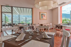 A restaurant with tables set for dining, a view of the city, and a painting on the wall. - Hotel Las Aguilas Tenerife, Affiliated by Melia (Puerto de la Cruz)