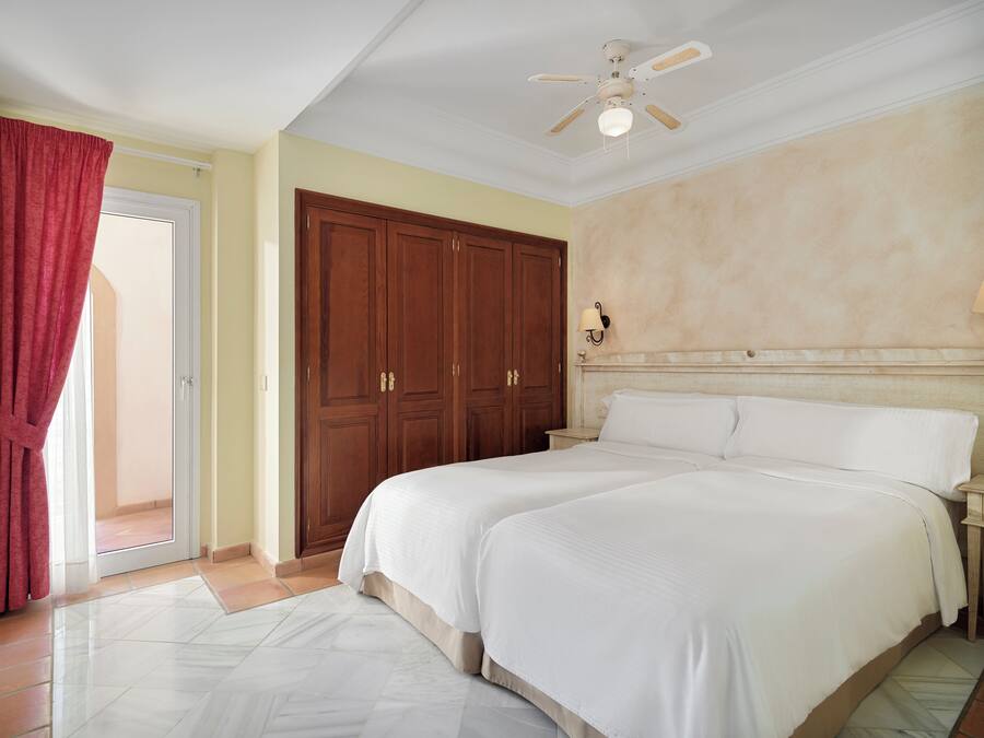 Un dormitorio con una cama grande, un ventilador de techo y un armario.