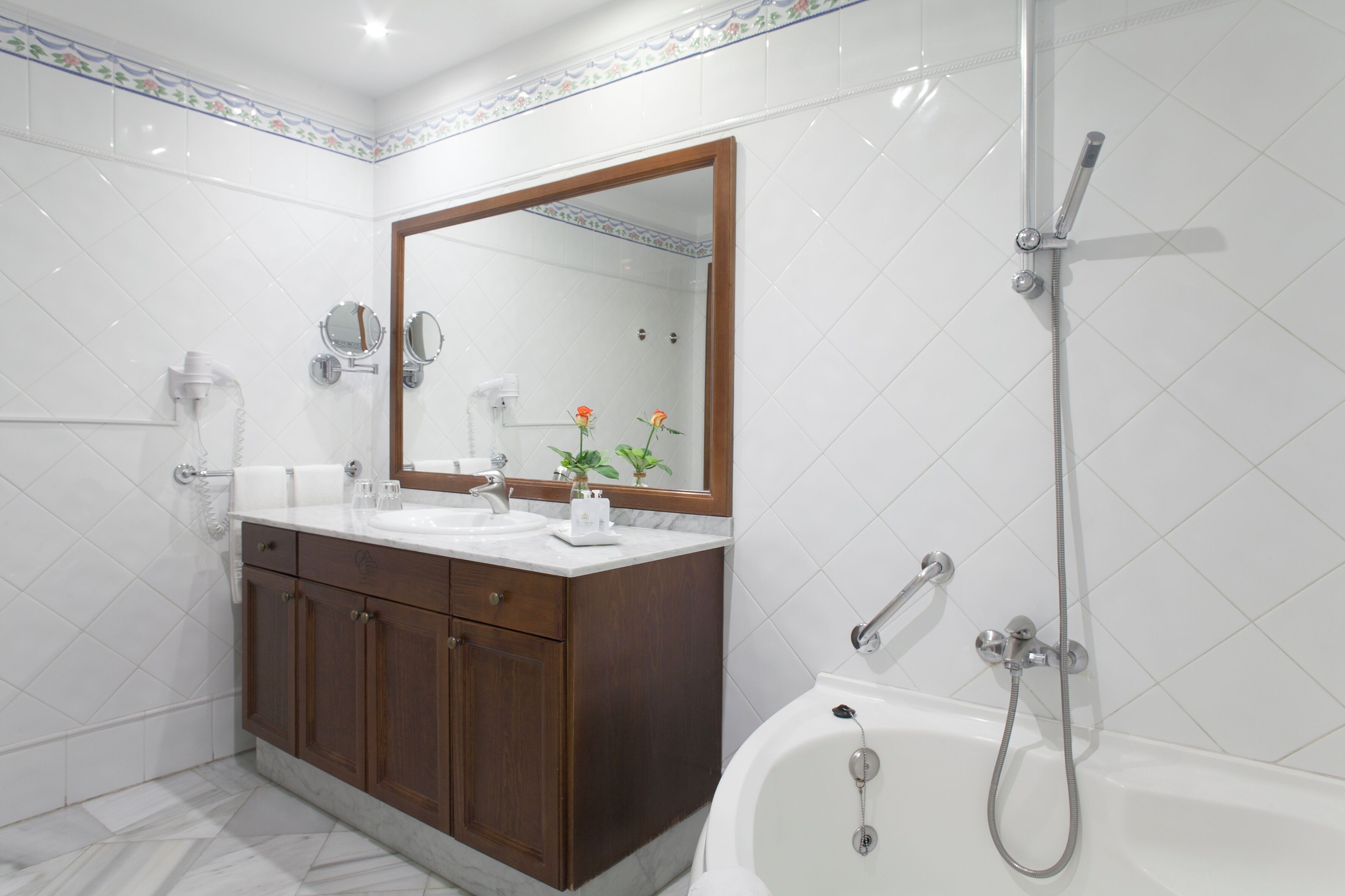 Un baño moderno con tocador de doble lavabo, un espejo grande, ducha con cabezal de ducha manual y bañera.