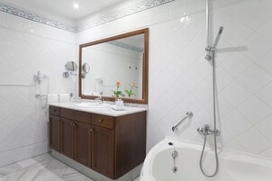Un baño moderno con tocador de doble lavabo, un espejo grande, ducha con cabezal de ducha manual y bañera.