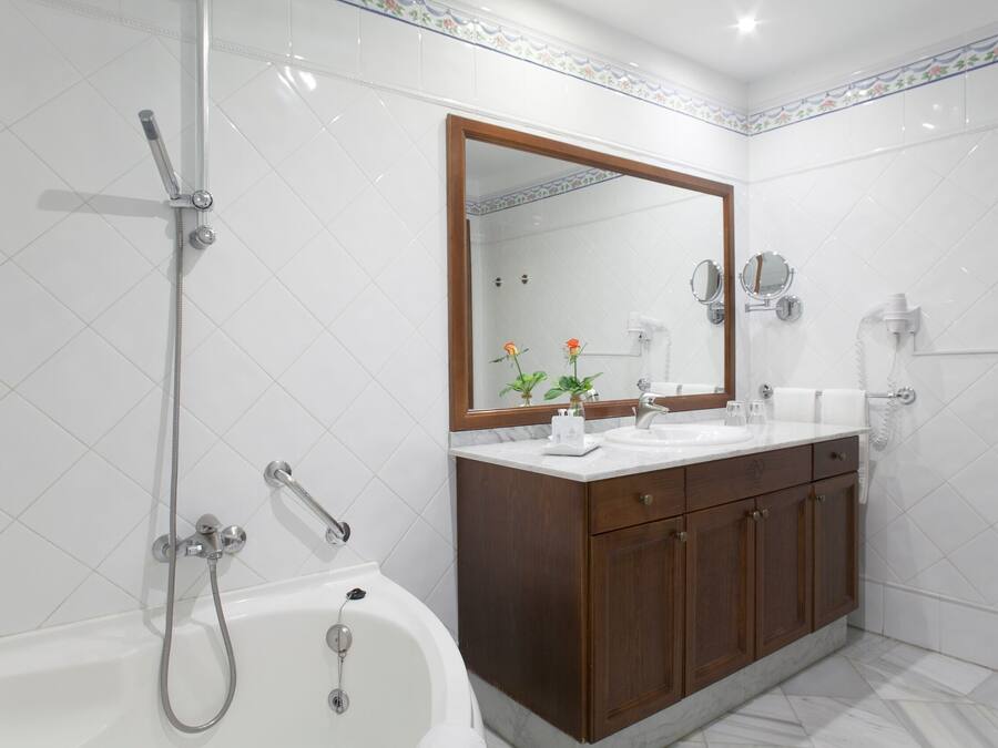 Un baño moderno con bañera, un espejo grande y un mueble de tocador de madera.