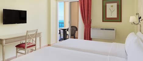 A hotel room with two beds, a desk with a chair, a television, an air conditioning unit, and a balcony with a view.
