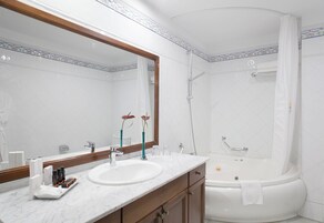 Un baño con dos lavamanos, un espejo grande, una bañera y una ducha.