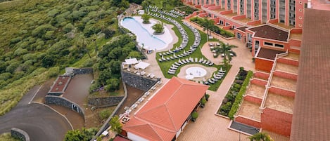 A hotel with a swimming pool, a landscaped garden, and a large building with multiple balconies.