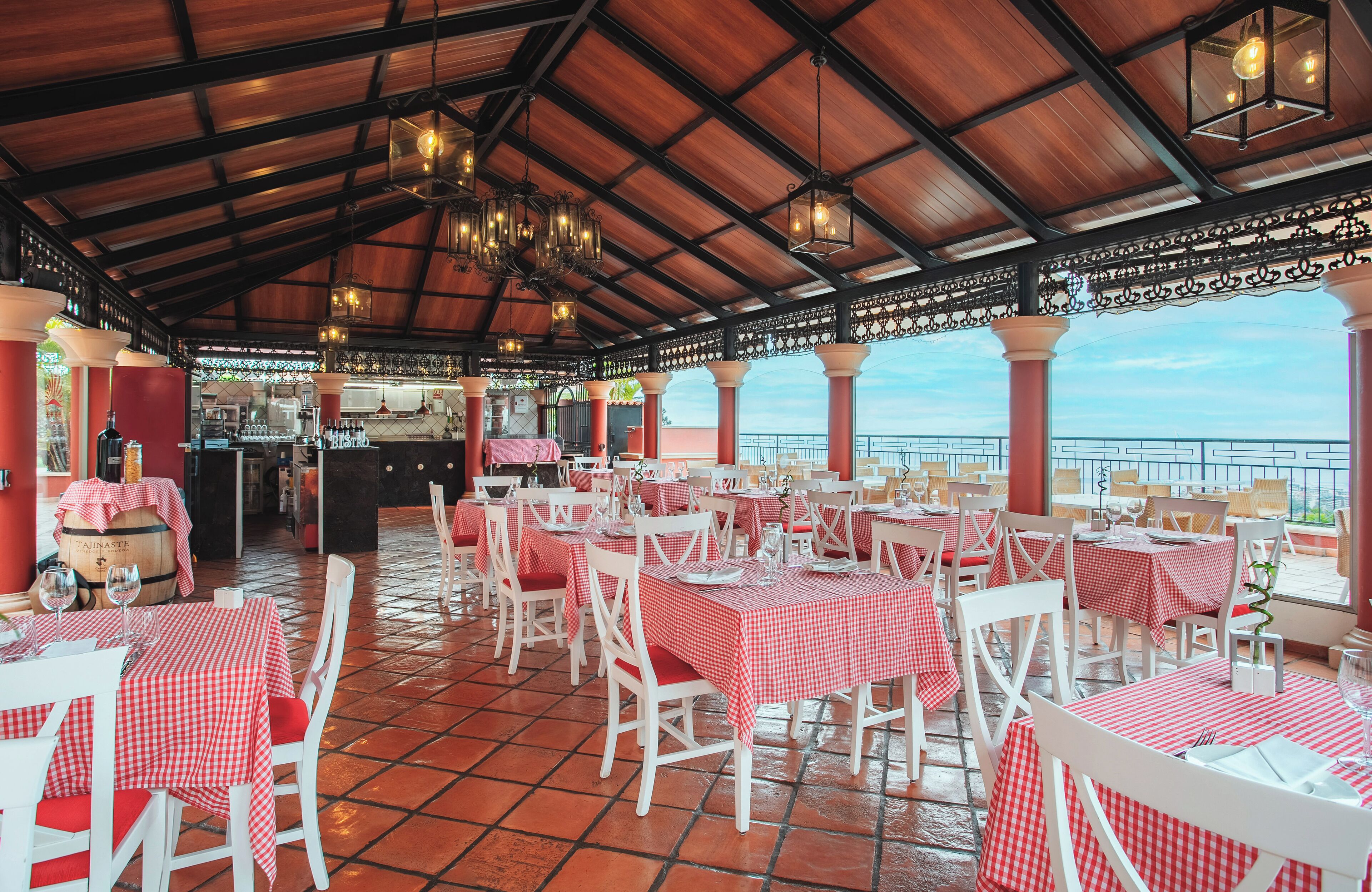 A restaurant with red and white checkered tablecloths, white chairs, and a tiled floor.