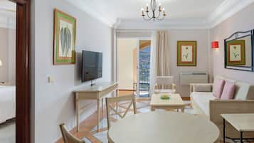 A hotel room with a bed, a TV, a dining table, a sofa, and a balcony with a view.