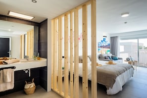 A modern hotel room with a large bed, a separate bathroom, a large window, and a view of the city. - Hotel Taimar (Pajara)