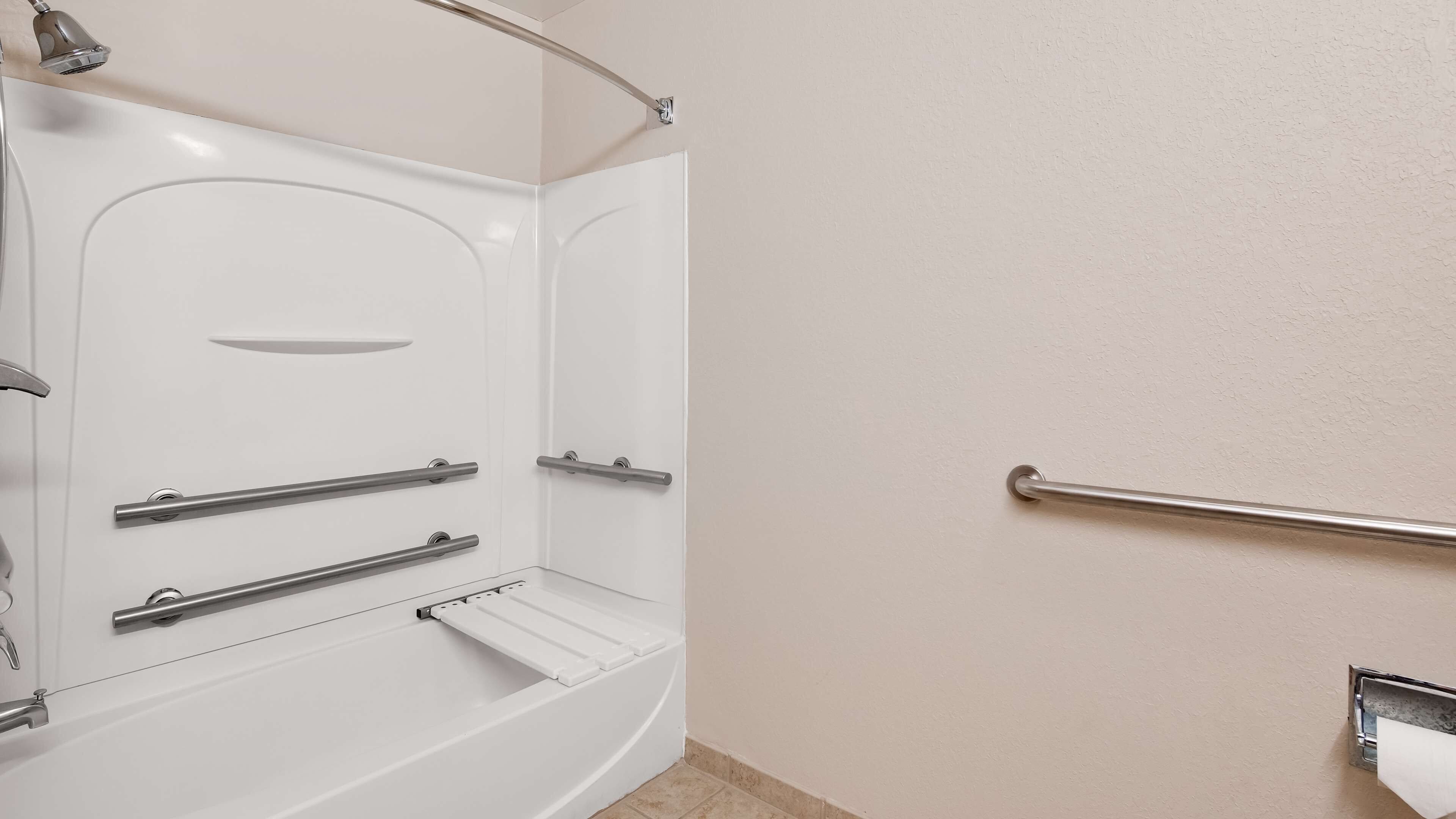 Une salle de bain moderne dotée d’une douche à l’italienne, de barres d’appui et d’un porte-serviettes.